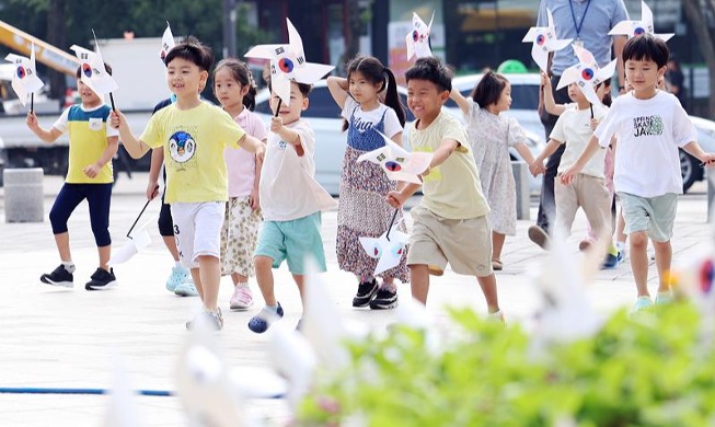 Children run with pinwheels of national flag